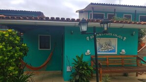 A building with a turquoise facade, a hammock, and a wooden bench. - OYO Pousada Encanto dos Anjos (Búzios)