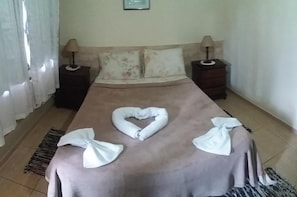 A neatly made bed with a heart-shaped towel and two bow ties on the bedspread. - OYO Pousada Encanto dos Anjos (Búzios)