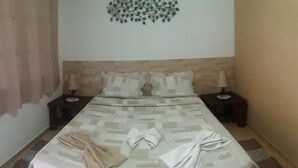 A neatly made bed with a patterned bedspread, two pillows, and a decorative wall piece above. - OYO Pousada Encanto dos Anjos (Búzios)