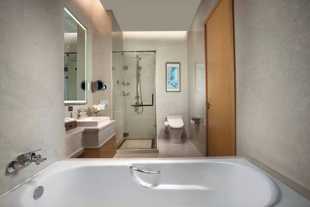 A modern bathroom with a large bathtub, a glass-enclosed shower, and a toilet.