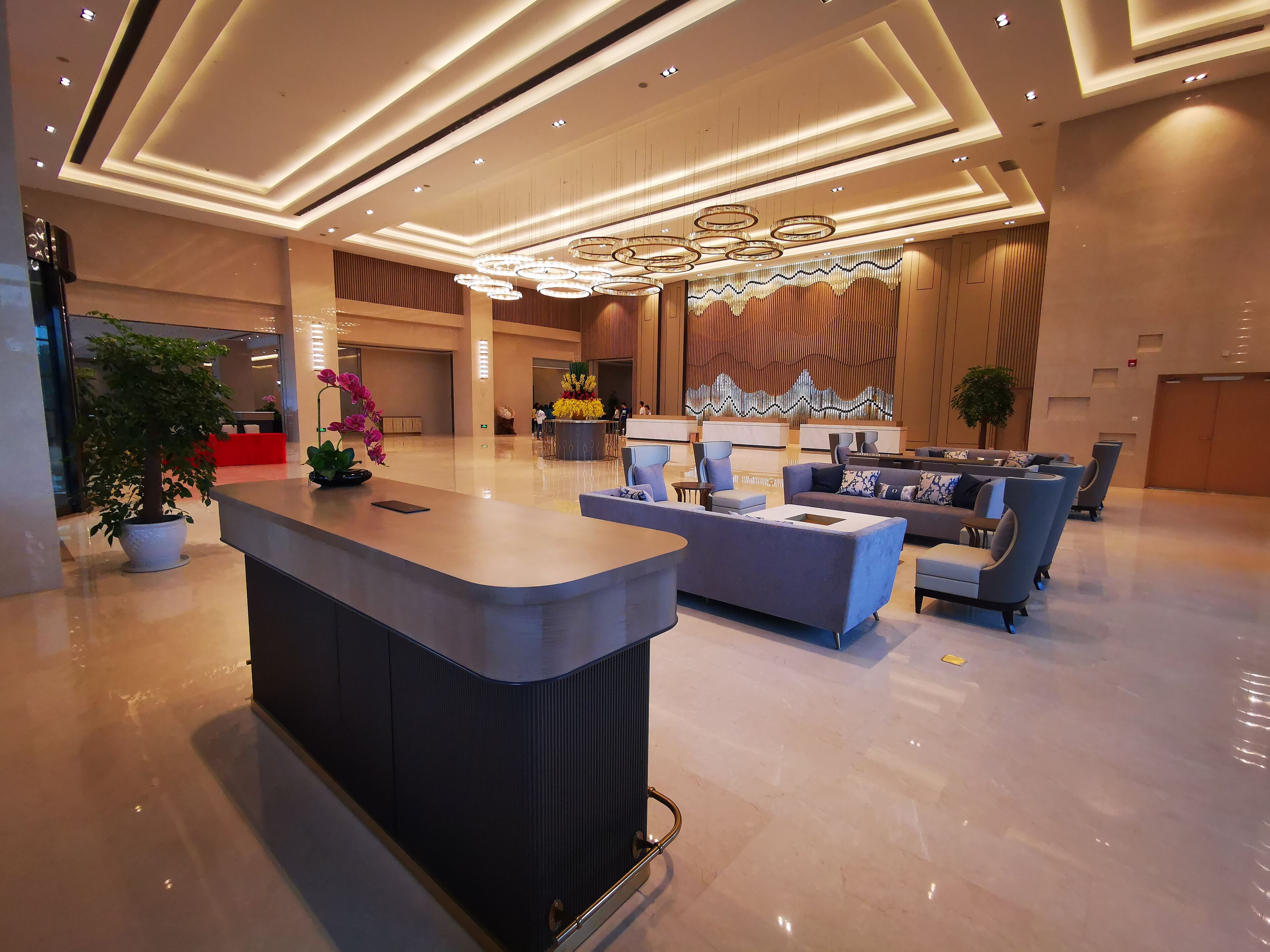 Una hall moderna con reception, area salotto e illuminazione decorativa.