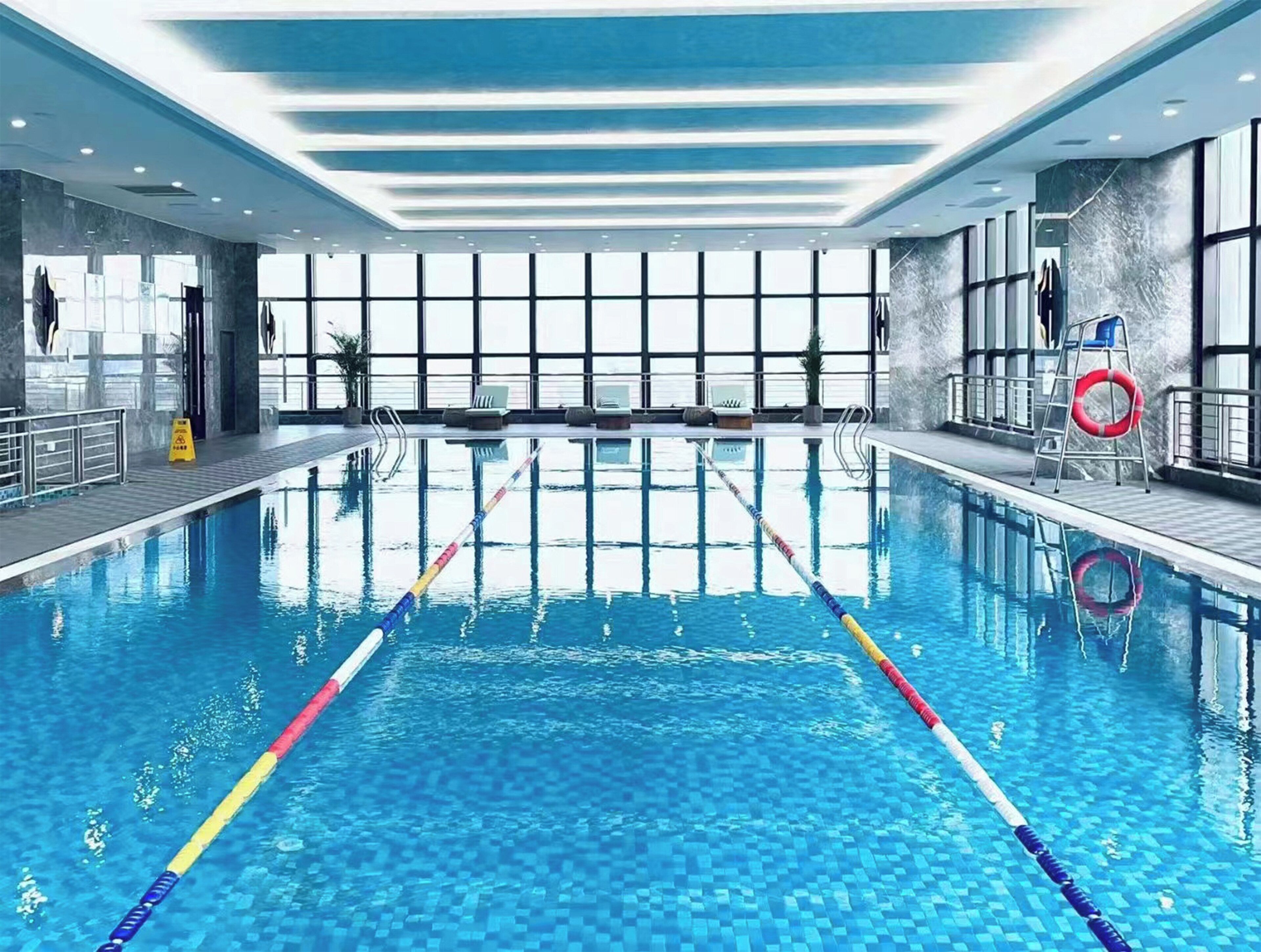 Una amplia piscina interior con divisiones de carril, un flotador salvavidas y una escalera.