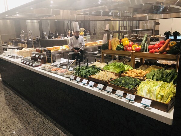 A buffet area with various food items and a chef preparing food. - Holiday Inn Jiashan by IHG (Jiaxing)
