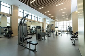 A spacious gym with various exercise machines, large windows, and a high ceiling with wooden slats. - Holiday Inn Jiashan by IHG (Jiaxing)