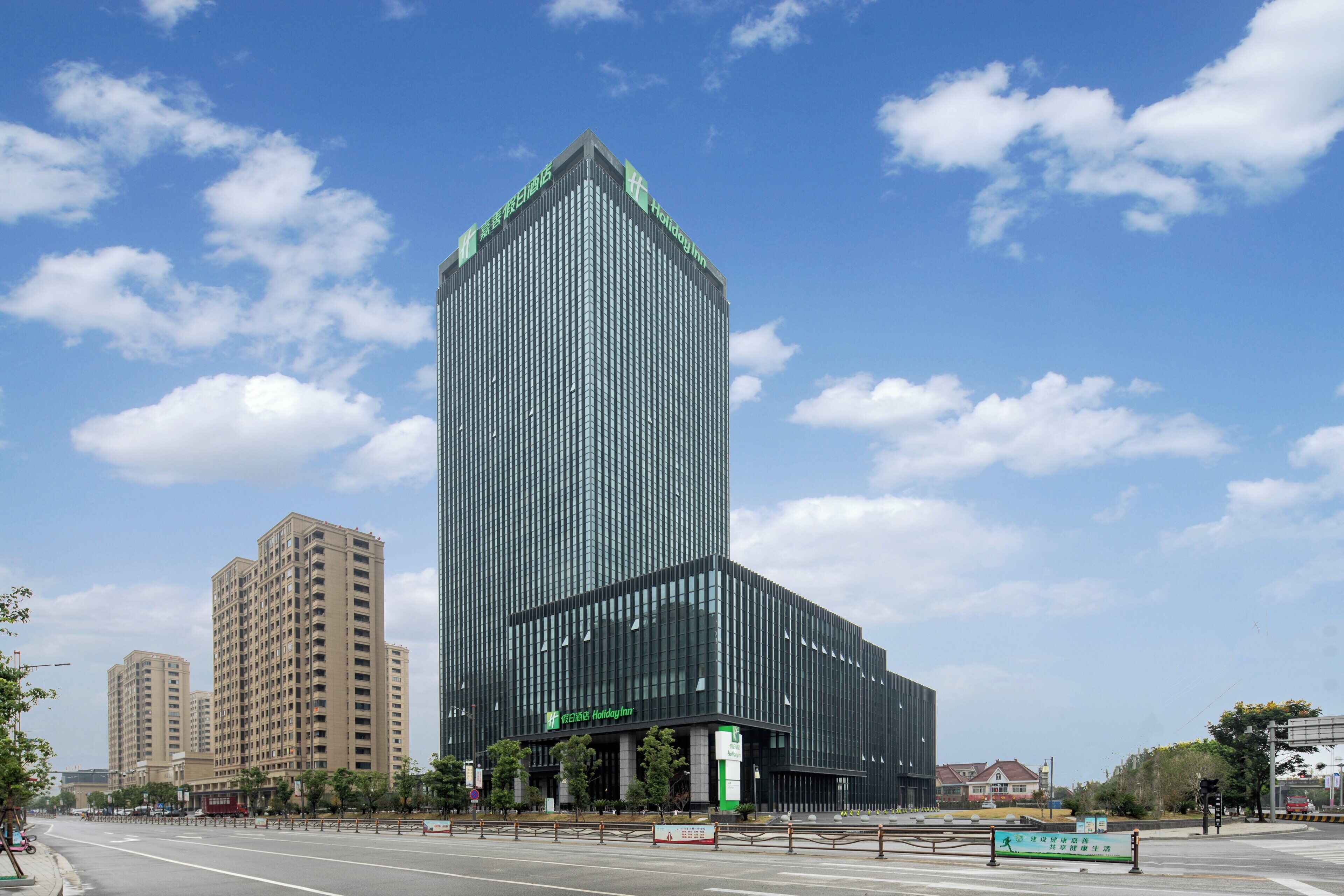 A modern hotel with a prominent vertical design, located at a city intersection.