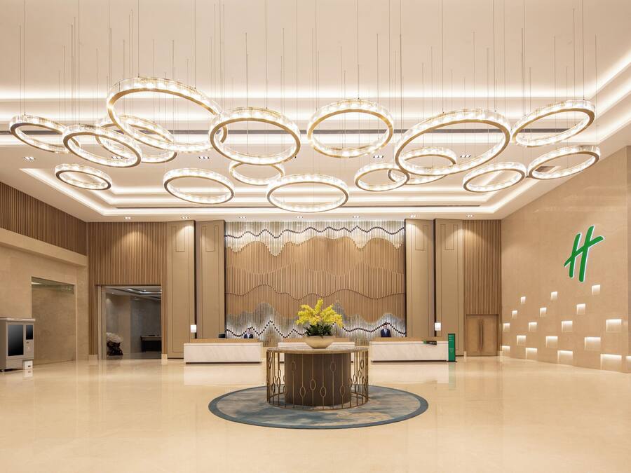 Un vestíbulo moderno con una recepción, un muro decorativo y varios apliques circulares.