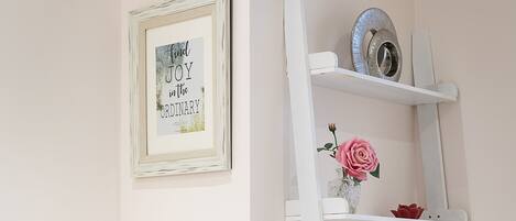 A white ladder shelf with decorative items and a framed quote on the wall.