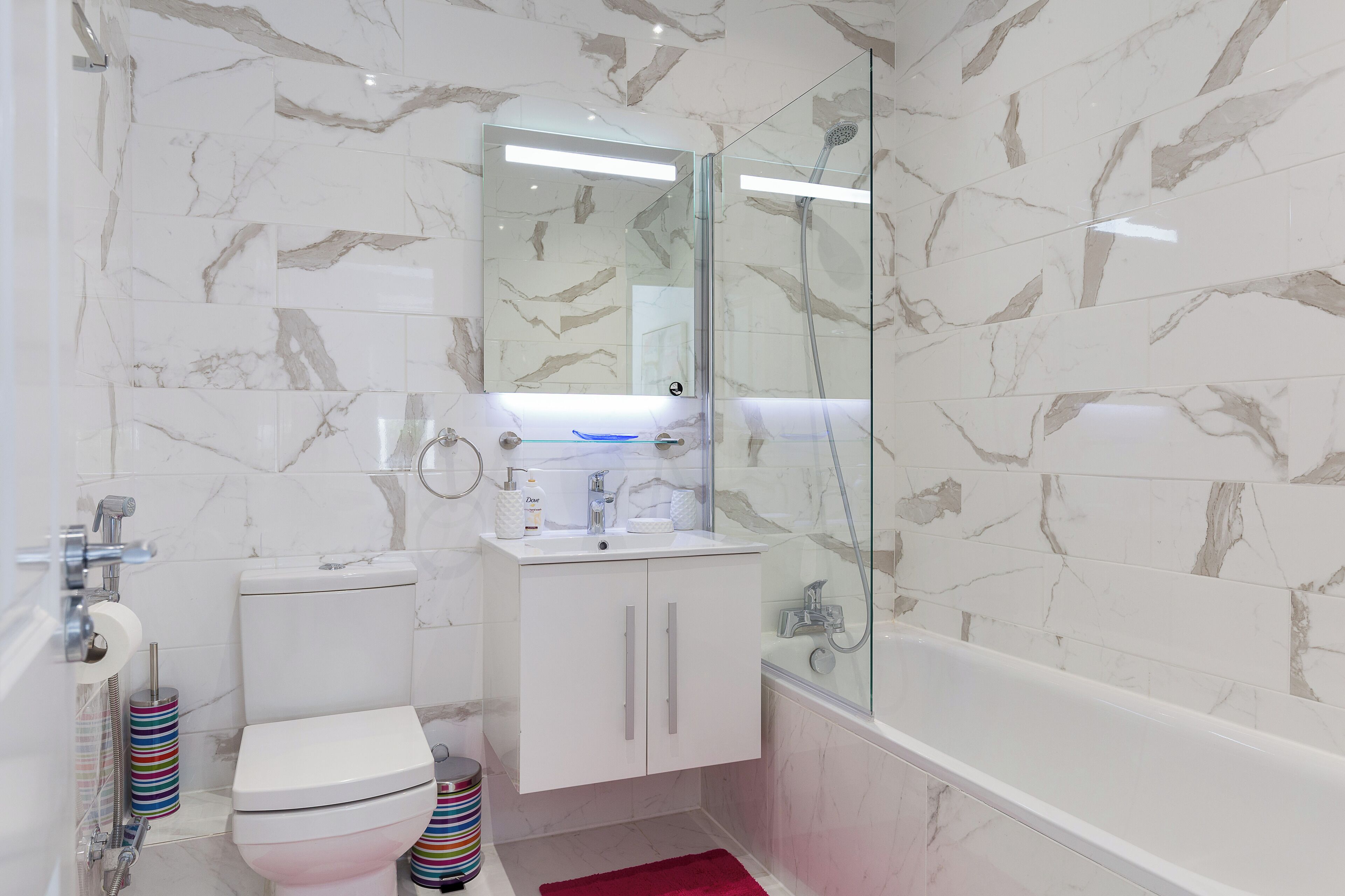 Baño con inodoro, lavabo y bañera, todo con azulejos de mármol.