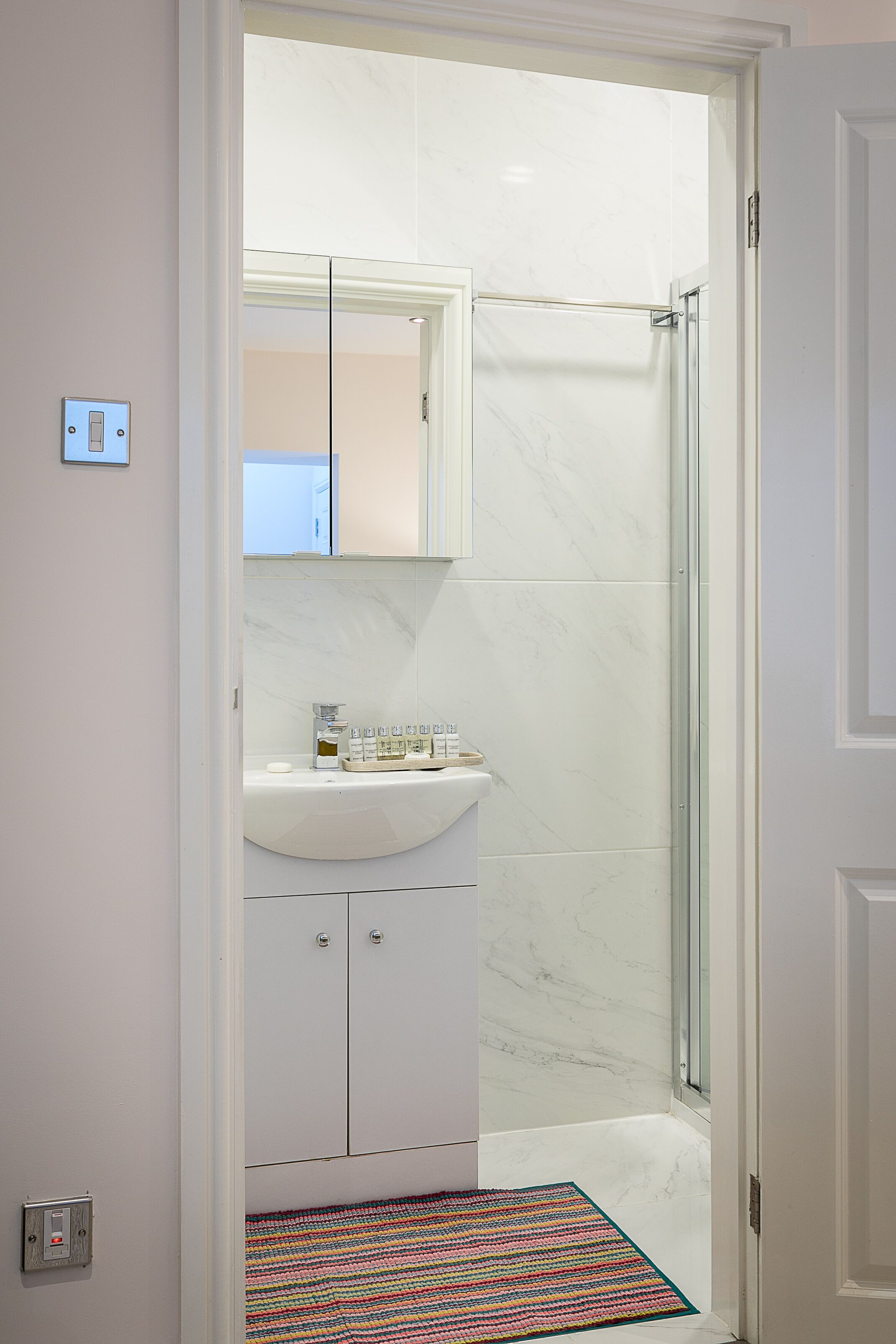 A bathroom with a white sink, mirror, and shower.