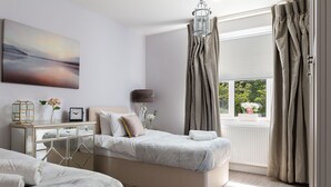 Une chambre à coucher avec un grand lit, des tables de chevet, un miroir et une fenêtre avec des rideaux.