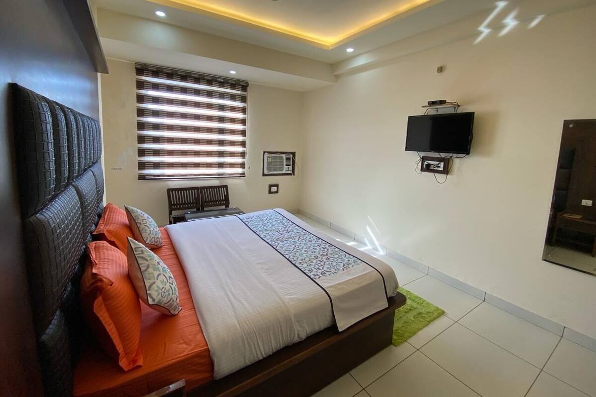 Un dormitorio moderno con cama, ventilador de techo, televisor y ventana con persianas.