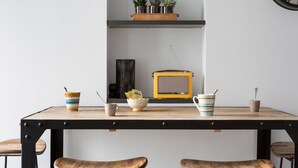 Una mesa de comedor con sillas, un radio y una estantería con plantas.