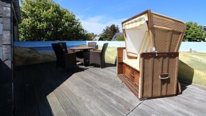 Uma área de estar coberta ao ar livre com móveis de vime e vista para o mar.