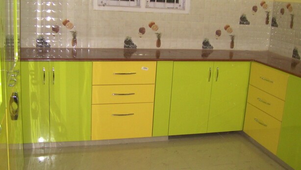 Una cocina con gabinetes amarillos, una ventana y un rebozado de azulejos.
