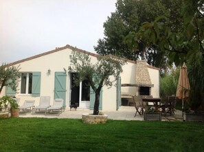 Una casa con patio, mobiliario exterior y chimenea de piedra.