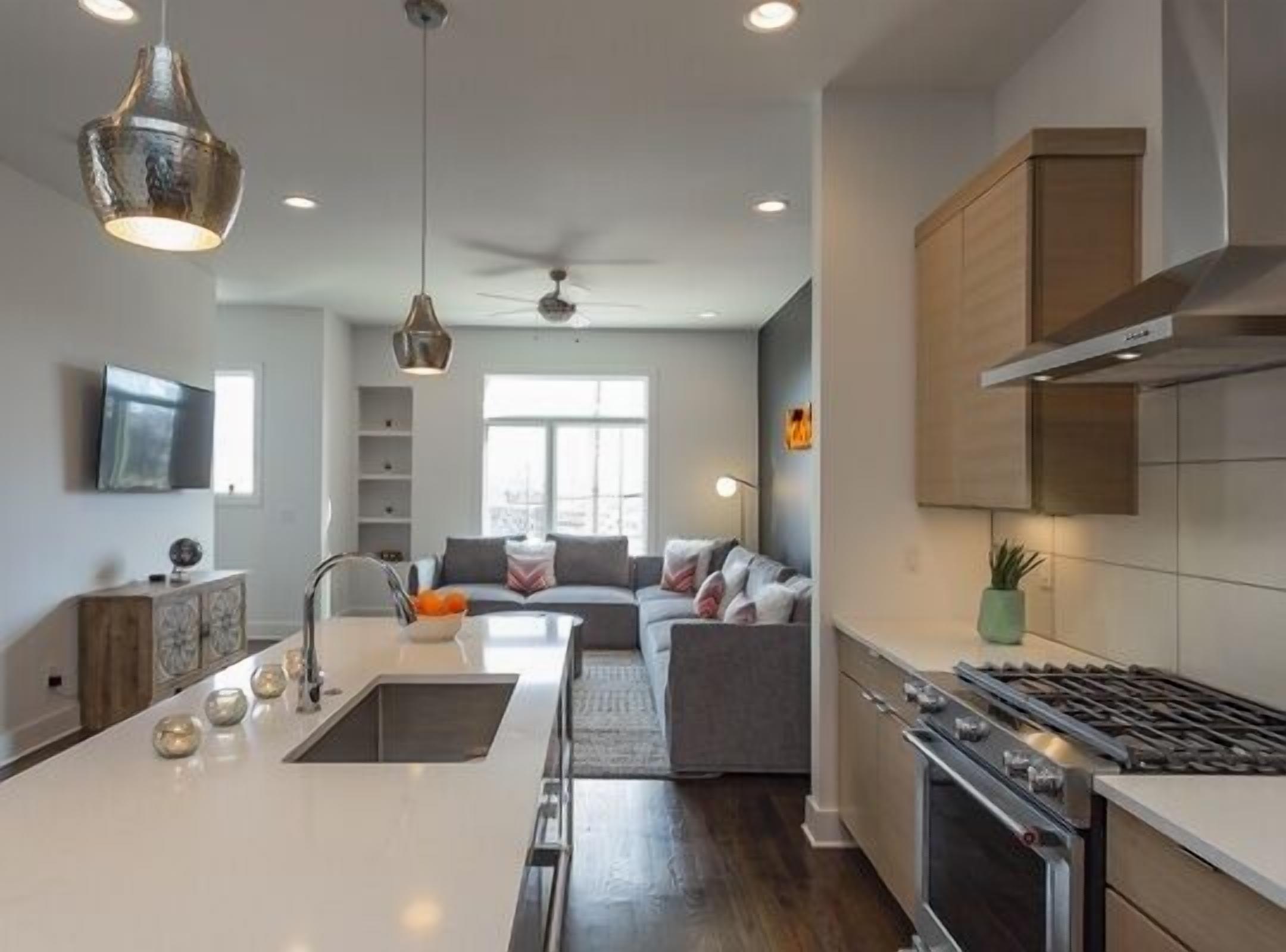 A modern kitchen with a central island, built-in oven, and a ceiling fan.