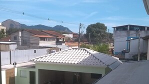 A residential area with a tiled roof, a small covered outdoor area, and a distant view of a hill.