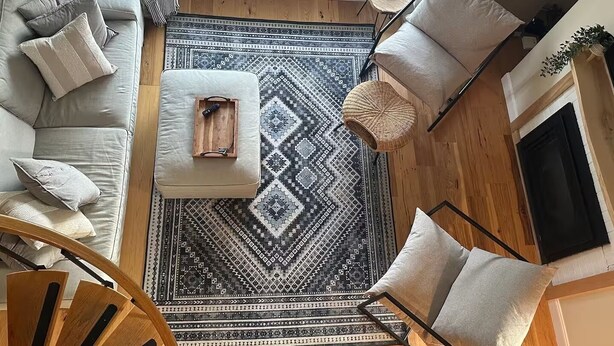 A cozy living room with a large window, a patterned rug, a wooden coffee table, and a sofa with cushions. - Sugarbush Mountainside Retreat - Ski in ski out (Warren)