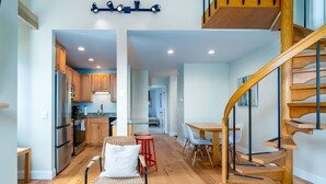 A spacious kitchen with modern appliances, a dining area with a wooden table and chairs, and a wooden staircase. - Sugarbush Mountainside Retreat - Ski in ski out (Warren)