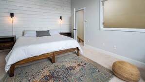 A bedroom with a bed, two bedside tables, a rug, and a large window. - Sugarbush Mountainside Retreat - Ski in ski out (Warren)