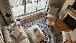 A modern living room with a large window, a sofa set, a patterned rug, a fireplace, and a TV. - Sugarbush Mountainside Retreat - Ski in ski out (Warren)