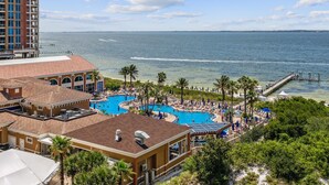 Een resort met een groot zwembad, palmbomen en uitzicht op de oceaan.