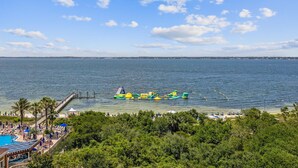Een strand met een pier, een zwembad en een waterpark met opblaasbare attracties.
