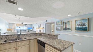 A kitchen with granite countertops, a dishwasher, and light blue walls.