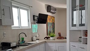 Une cuisine avec des armoires blanches, une cuisinière noire, un ventilateur de plafond et une fenêtre.