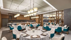 Un comedor amplio con mesas redondas, sillas color turquesa y una lámpara moderna.