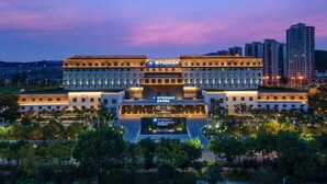 Un hotel de varios pisos con un llamativo letrero 'WYNDHAM', que presenta una fachada simétrica, varios balcones y un patio ajardinado.