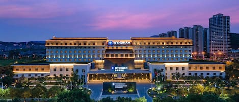 A multi-story hotel with a prominent 'WYNDHAM' sign, featuring a symmetrical facade, multiple balconies, and a landscaped courtyard.