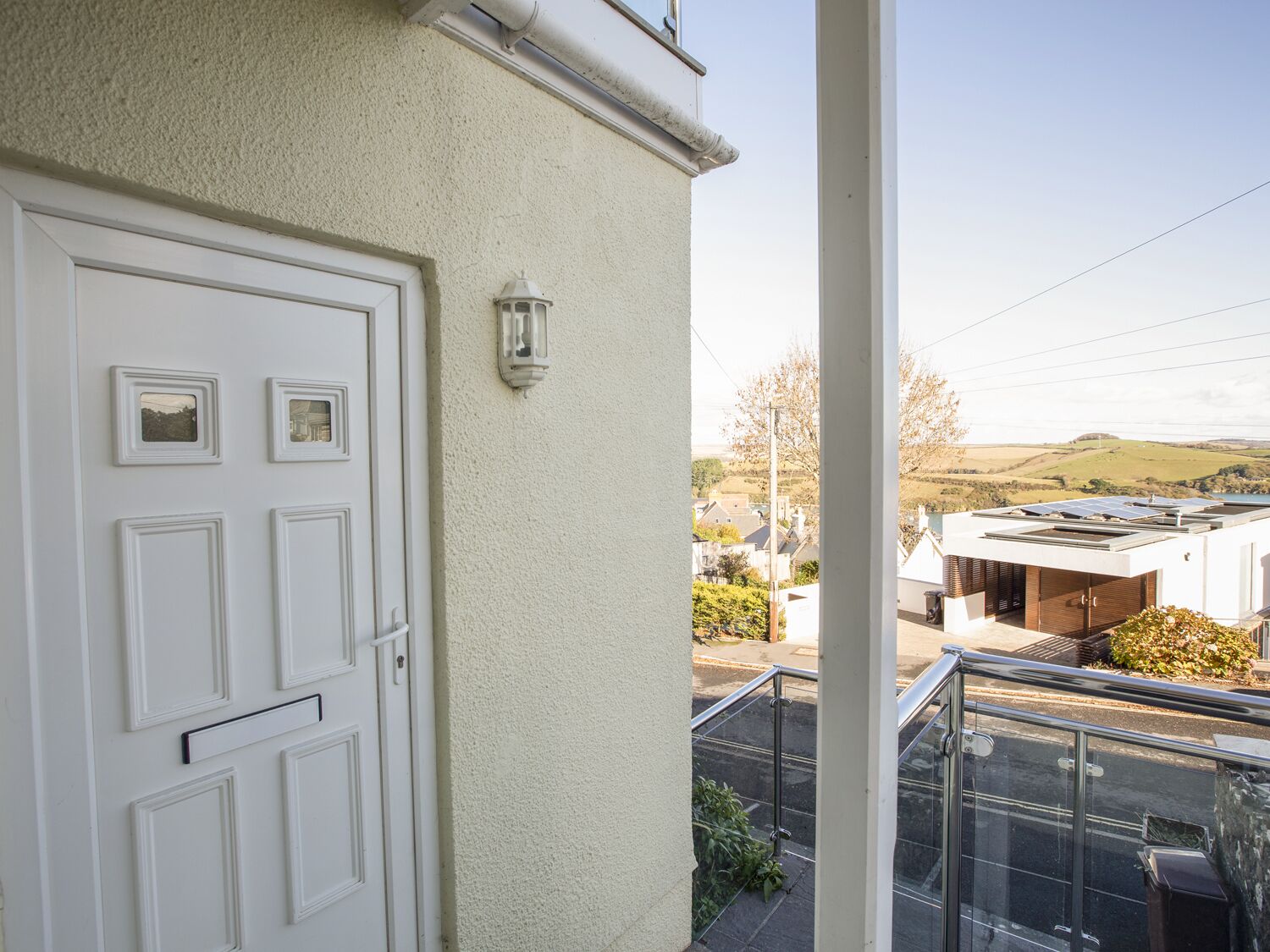 A white door with a small window and a wall-mounted light fixture.