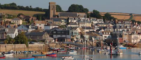 A coastal town with a prominent tower, a marina with various boats, and a dense cluster of houses.