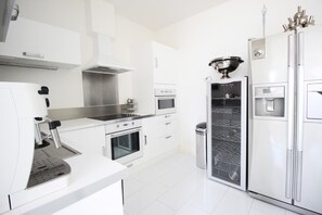 Una cocina moderna con electrodomésticos de acero inoxidable, incluyendo una cafetera, horno y refrigerador.