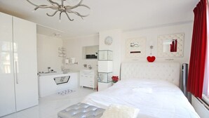 Un dormitorio moderno con una cama grande, un tocador con espejo y un baño con bañera.