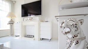 Una sala de estar moderna con chimenea, un televisor montado encima y una estatua decorativa de leopardo.