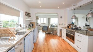 Una cocina moderna con suelo de madera, armarios blancos y electrodomésticos de acero inoxidable.