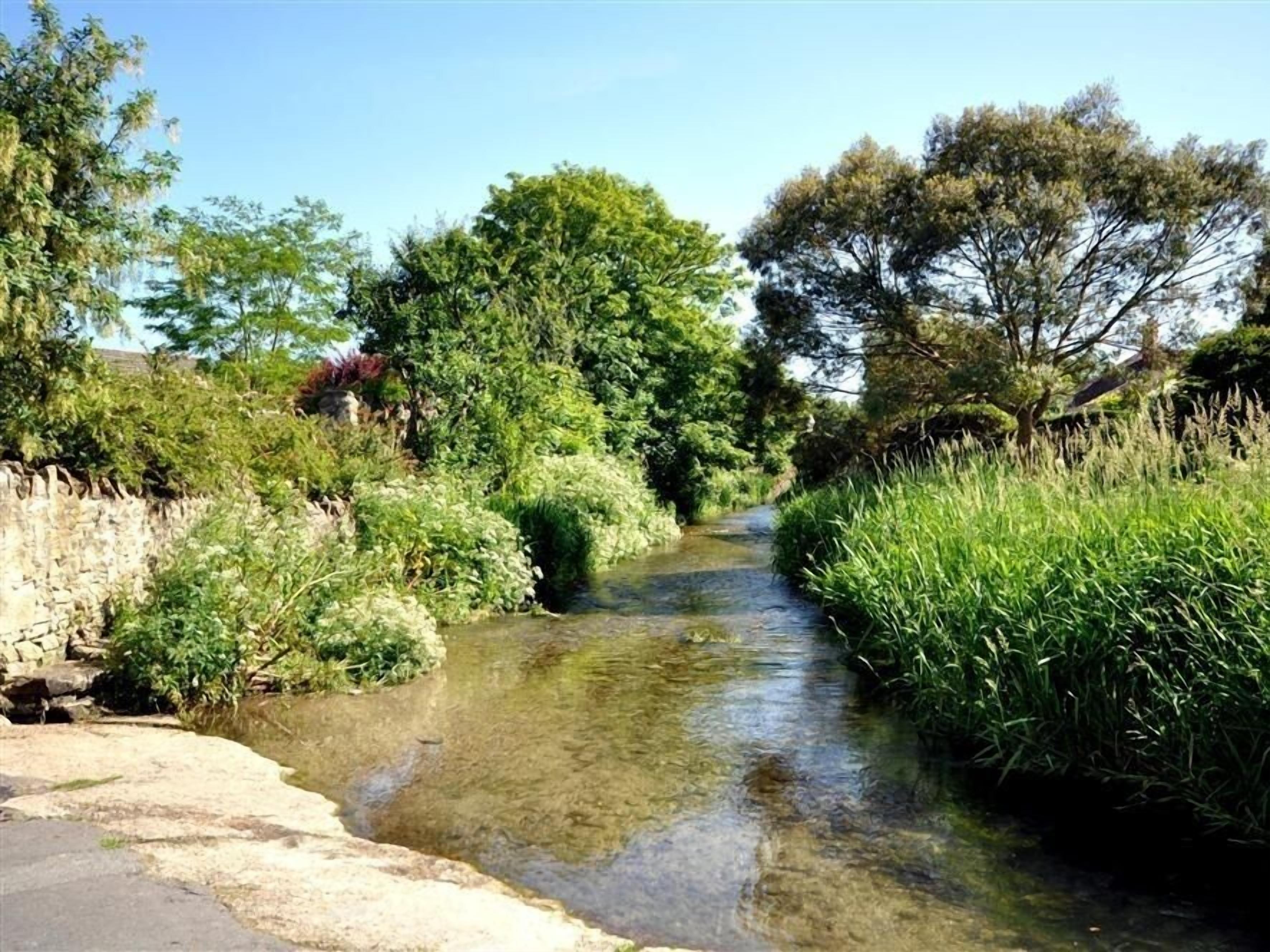 A narrow water channel flanked by lush greenery and stone walls.