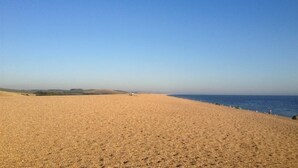Platja ampla i sorrenca amb un cel blau clar i mar tranquil·la.