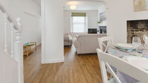 Un salón amplio con un sofá, una mesa de comedor para cuatro personas y una chimenea.