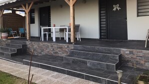 Une maison moderne dotée d’un porche abrité, d’un escalier en pierre et d’un coin repas avec une table et des chaises.