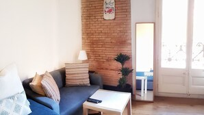 A living room with a brick wall, a sofa, a coffee table, and a door with a view. - Homestay CityCenter (Barcelona)