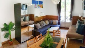 A living room with a sofa, a dining table with chairs, a TV, and a potted plant. - Homestay CityCenter (Barcelona)