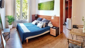 A bedroom with a bed, bedside table, nightstand, TV, potted plant, and a view of the outdoors. - Homestay CityCenter (Barcelona)