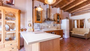 A kitchen with wooden cabinets, a white countertop, a hanging light fixture, and a tiled backsplash. - Monte Verde Ojén by Ruralidays (Málaga)