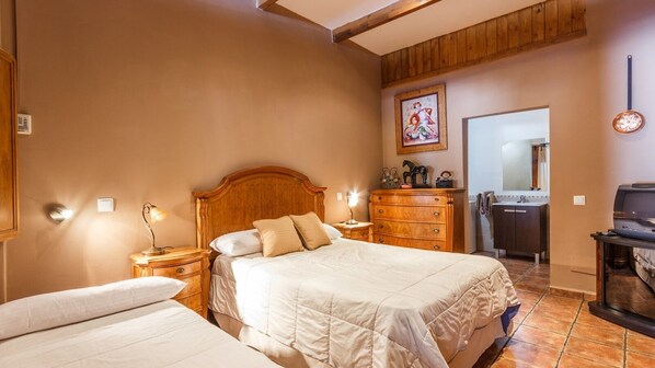 Une chambre d’hôtel avec deux lits, des têtes de lit en bois, une commode, un miroir et un téléviseur.