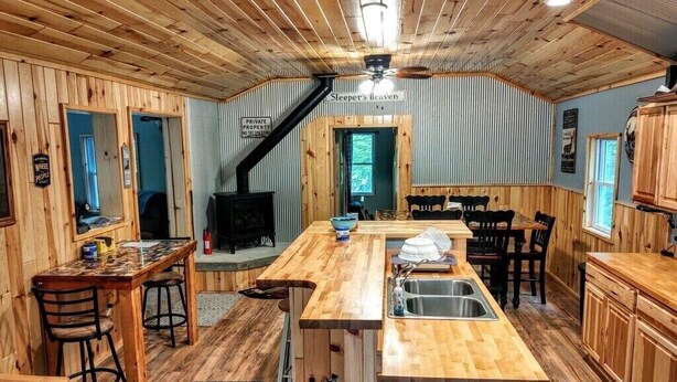 Un interior acogedor estilo cabaña, con una zona de comedor de madera, una cocina con fregadero y una chimenea.