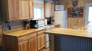 Una cocina con armarios de madera, estufa, refrigerador y una decoración con cabeza de venado.