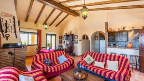 A spacious living room with a brick fireplace, two striped sofas, and a wooden coffee table. - Villa Calena Almuñécar by Ruralidays (Granada)